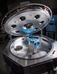alt = Open view of a SCARA (Selective Compliance Assembly Robot Arm) system. It has a large circular lid and a machined interior for automated processes.