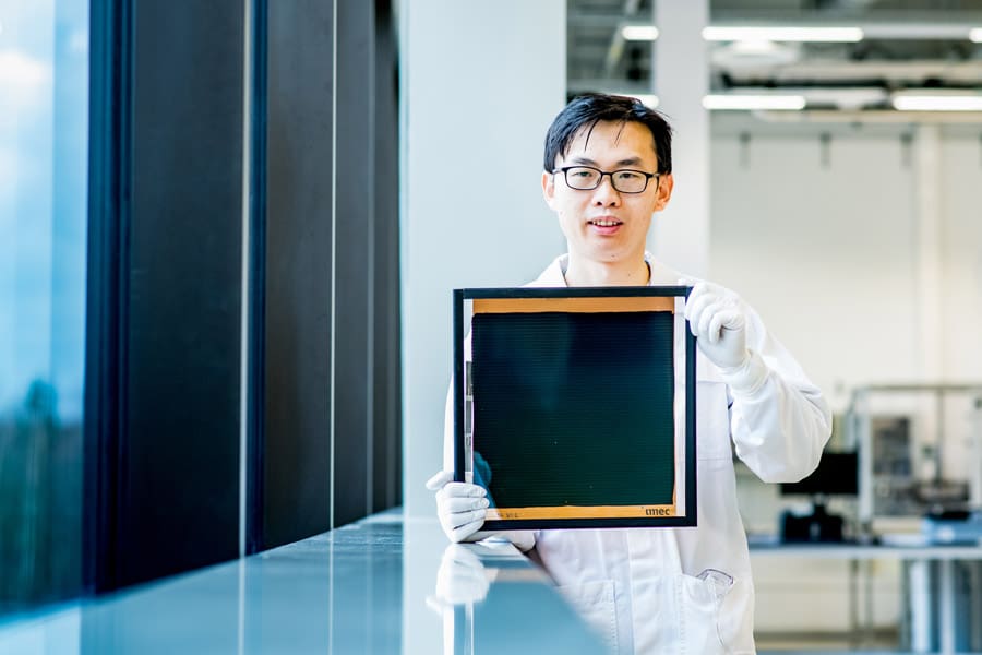 30x30cm2-perovskite-module_imec_researcher Alt text: A researcher holds a large 30x30 cm² perovskite module, demonstrating the advanced capabilities and research of the company's thin film deposition systems. The researcher, dressed in a lab coat and gloves, showcases the module in a laboratory setting, showcasing Angstrom Engineering's commitment to innovation in perovskite solar cell technology.