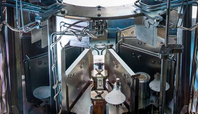 perovskite-cooling-deposition-unsmushed alt = Interior of a deposition for perovskite materials. There are cooling systems and holders as well as wiring and connectors. It is a careful and precise process manufactured by Angstrom Engineering.